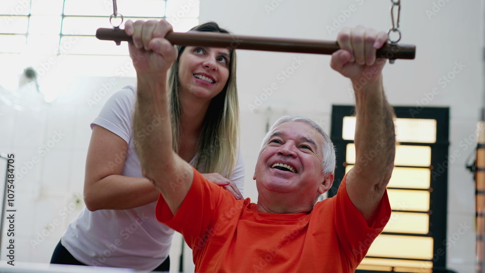 Fototapeta premium Female Pilates Coach helping senior man to use machine, old person training muscle in sport lifestyle 