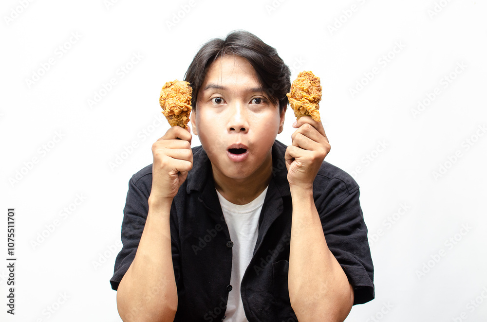 Hungry Young Asian Man eating and smelling Crispy Fried Chicken Thigh with a Look of Satisfaction. asian man eating crunchy fried chicken drumstick. Hungry Young Asian Man eating and smelling Crispy Fried Chicken Thigh with a Look of Satisfaction. asian man eating crunchy fried chicken drumstick.