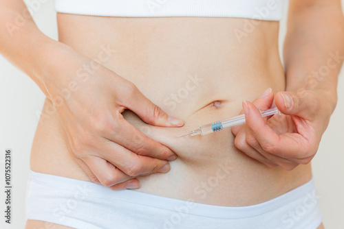 A young Caucasian woman in white underwear giving herself a subcutaneous injection into her stomach. Women's reproductive health. Trigger ovulation photo