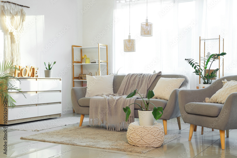 Obraz premium Interior of light living room with grey sofa, armchair and window
