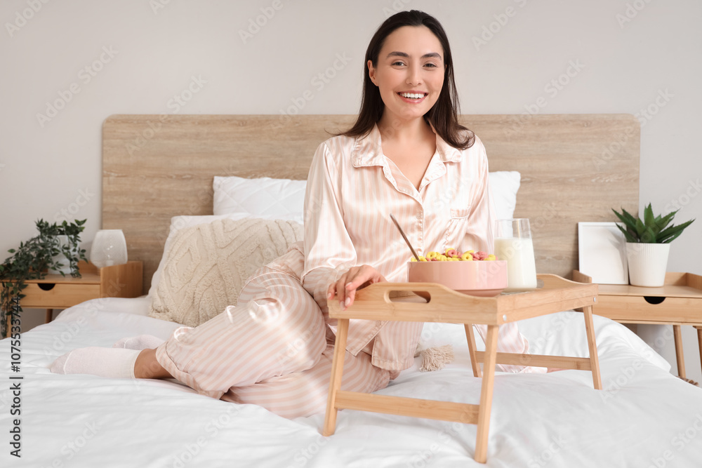 Morning of young woman in pajamas having breakfast on bed at home Morning of young woman in pajamas having breakfast on bed at home