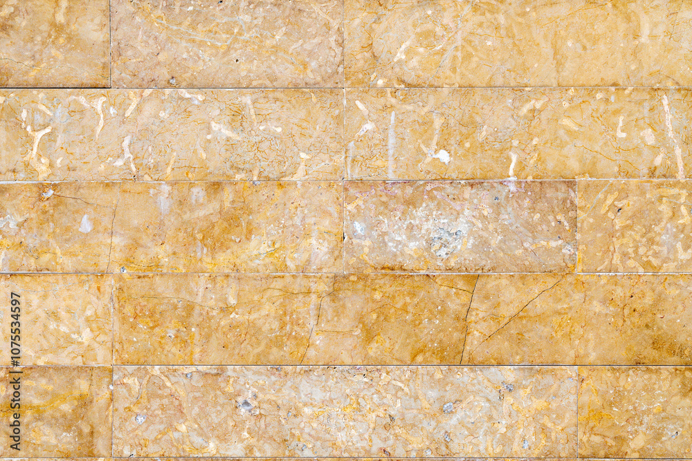 Fototapeta premium Yellow and brown stone wall with wear and tiny joints