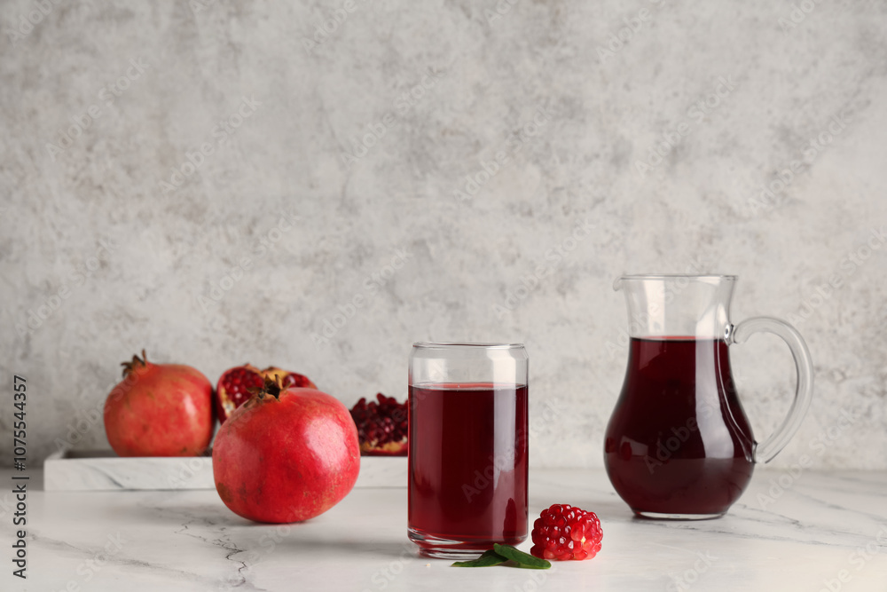 Glass and jug of fresh pomegranate juice on white background Glass and jug of fresh pomegranate juice on white background