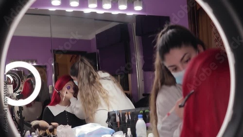 Makeup Artist Applying Character Makeup to Redhead Woman – Mid Shot Reflected in Mirror. Maquilladora Aplicando Maquillaje de Caracterización a Mujer Pelirroja – Plano Medio Reflejado en el Espejo
