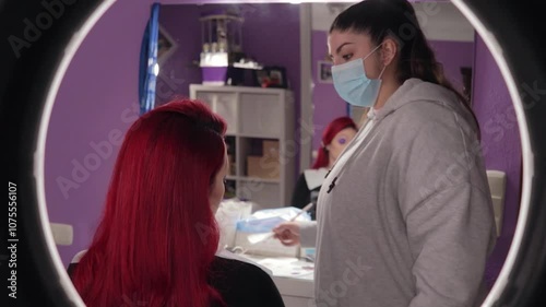 Makeup Artist Applying Character Makeup to Redhead Woman – Mid Shot Reflected in Mirror. Maquilladora Aplicando Maquillaje de Caracterización a Mujer Pelirroja – Plano Medio Reflejado en el Espejo
