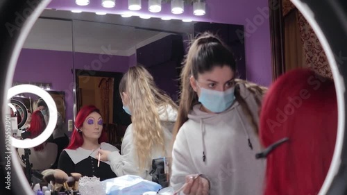 Makeup Artist Applying Character Makeup to Redhead Woman – Mid Shot Reflected in Mirror. Maquilladora Aplicando Maquillaje de Caracterización a Mujer Pelirroja – Plano Medio Reflejado en el Espejo
