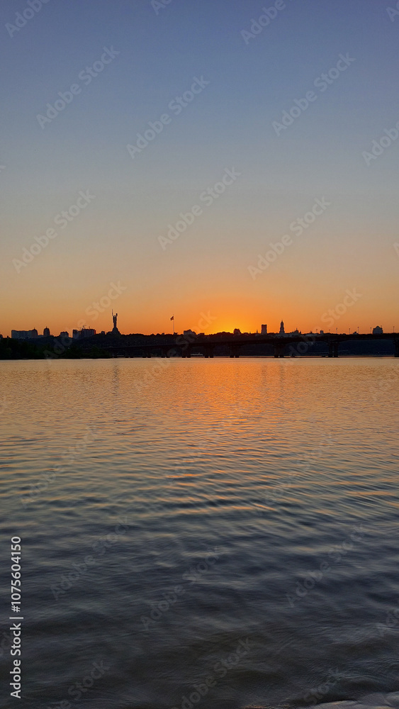 Sunset Over River with Silhouetted Cityscape and Monument Sunset Over River with Silhouetted Cityscape and Monument