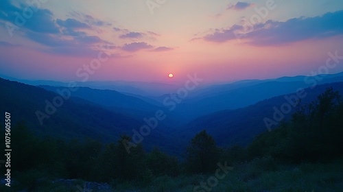 A vibrant sunset paints the sky over a mountain range, casting a warm glow across the landscape.