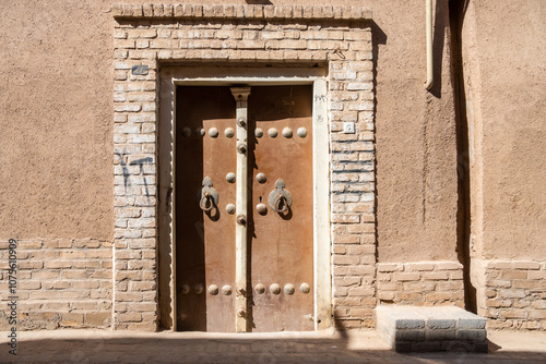 A sturdy wooden door set against a textured brick wall behind it, Yazd, Iran