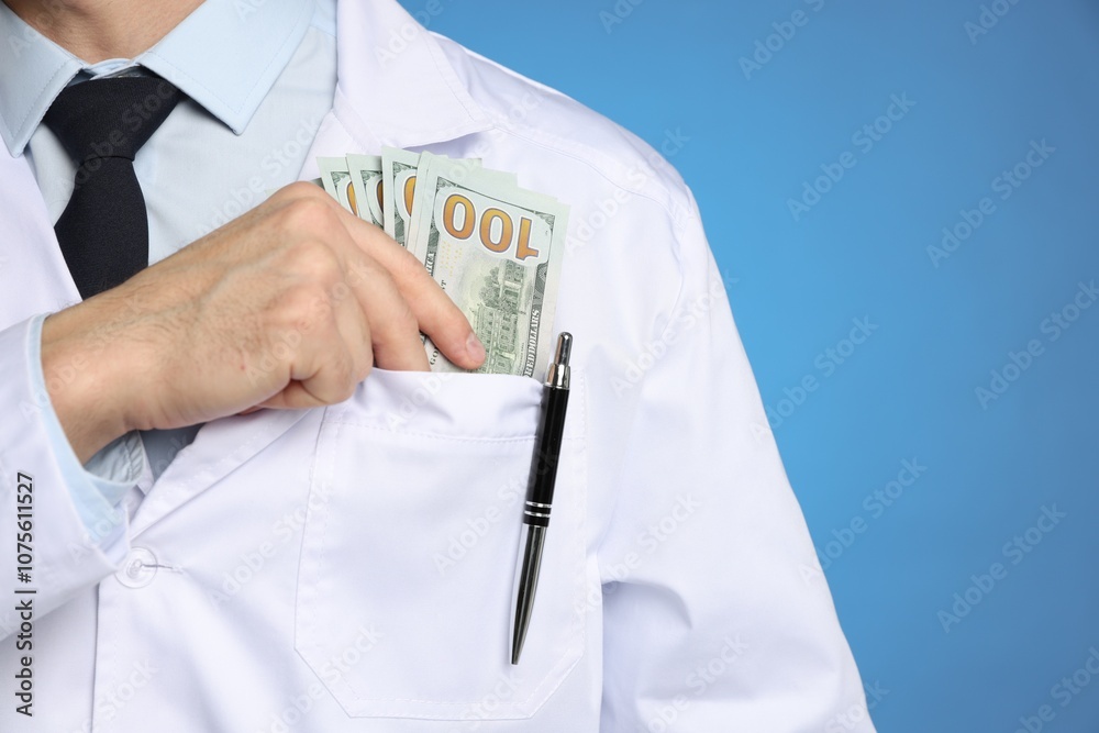 Corruption concept. Doctor putting dollar banknotes into his pocket on blue background, closeup