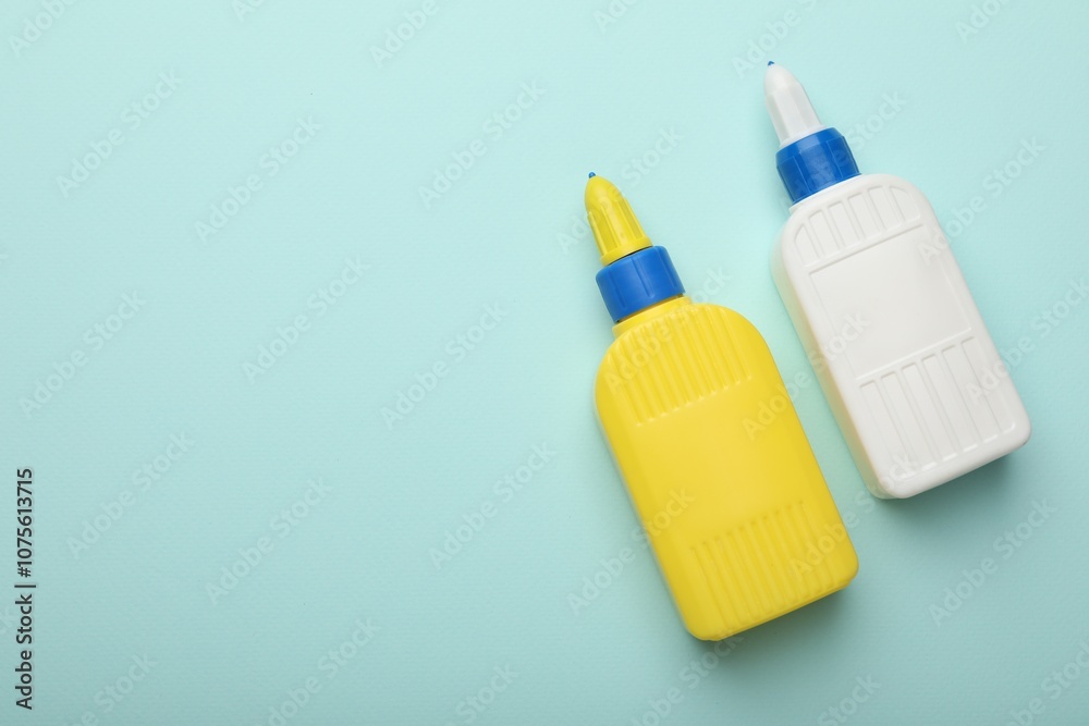 Bottles of glue on light blue background, top view. Space for text Bottles of glue on light blue background, top view. Space for text