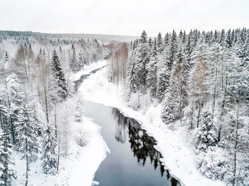 A serene winter landscape showing a winding river surrounded by dense, snow-covered trees. A serene winter landscape showing a winding river surrounded by dense, snow-covered trees.