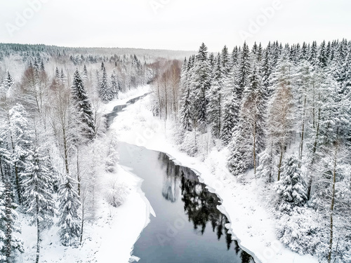 A serene winter landscape showing a winding river surrounded by dense, snow-covered trees.