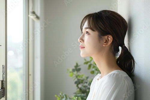 Side view photo of Asian woman admiring empty wall at home photo