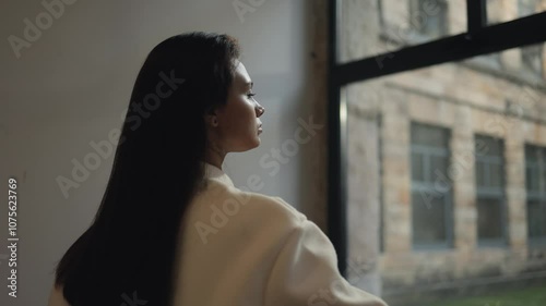 A beautiful girl by the window raises her head to a beam of light in a dark room, study, work, hope, melancholy, loneliness, confidence, a new stage, university, school, study, education