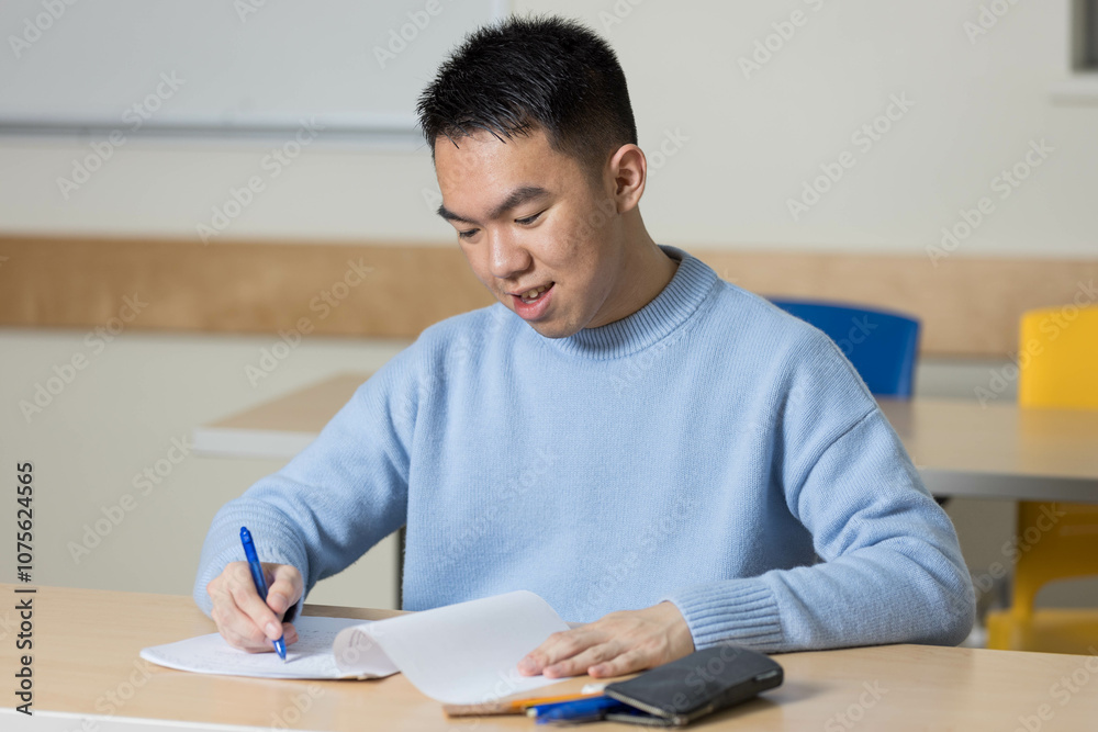 A man is sitting comfortably at a desk diligently writing on a piece of paper A man is sitting comfortably at a desk diligently writing on a piece of paper