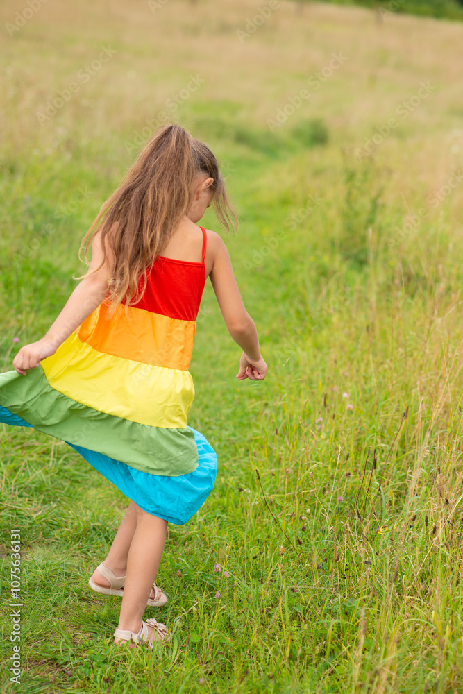 Fototapeta premium happy girl in a rainbow dress on the field
