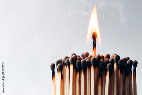 A lit match against the background of a group of other matches. Space for text.