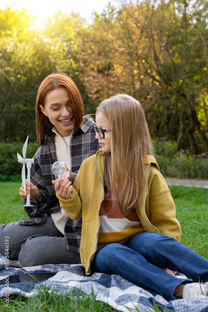 Little girl with teacher in park observing wind turbines learning about eco-friendly power sources Little girl with teacher in park observing wind turbines learning about eco-friendly power sources