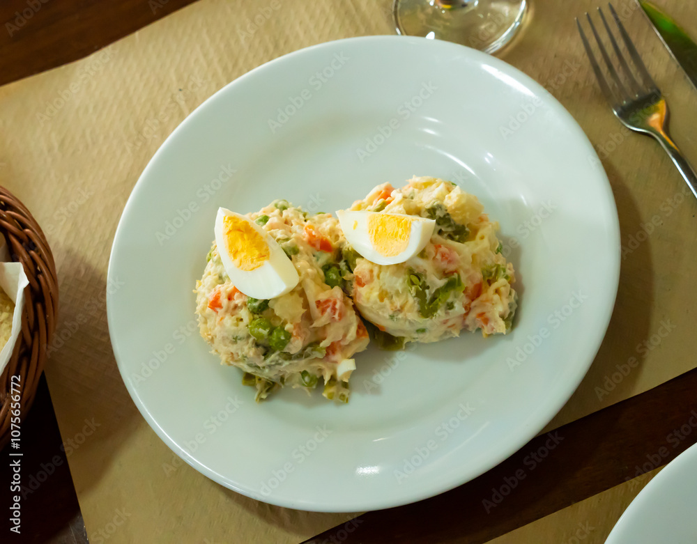 Ensalada rusa - salad with potatoes, tuna, green pea, olives and egg in a plate Ensalada rusa - salad with potatoes, tuna, green pea, olives and egg in a plate