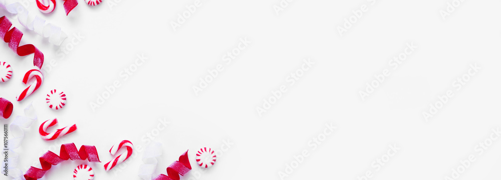 Christmas corner border of red and white ribbon and peppermint candy canes. Above view on a white banner background with copy space. Christmas corner border of red and white ribbon and peppermint candy canes. Above view on a white banner background with copy space.