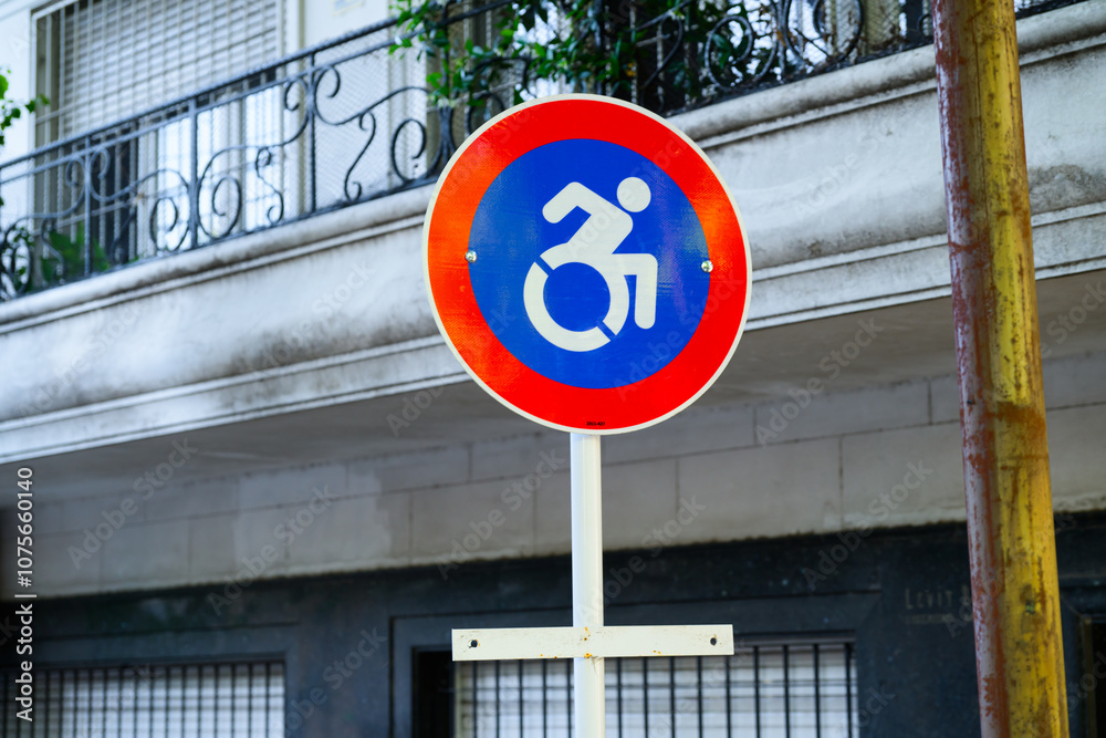 Naklejka premium There is a vividly colored red and blue sign featuring a representation of a handicapped individual in a wheelchair depicted on it