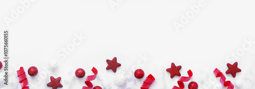 Christmas bottom border of red and white baubles and curly ribbon. Top view on a white banner background with copy space.