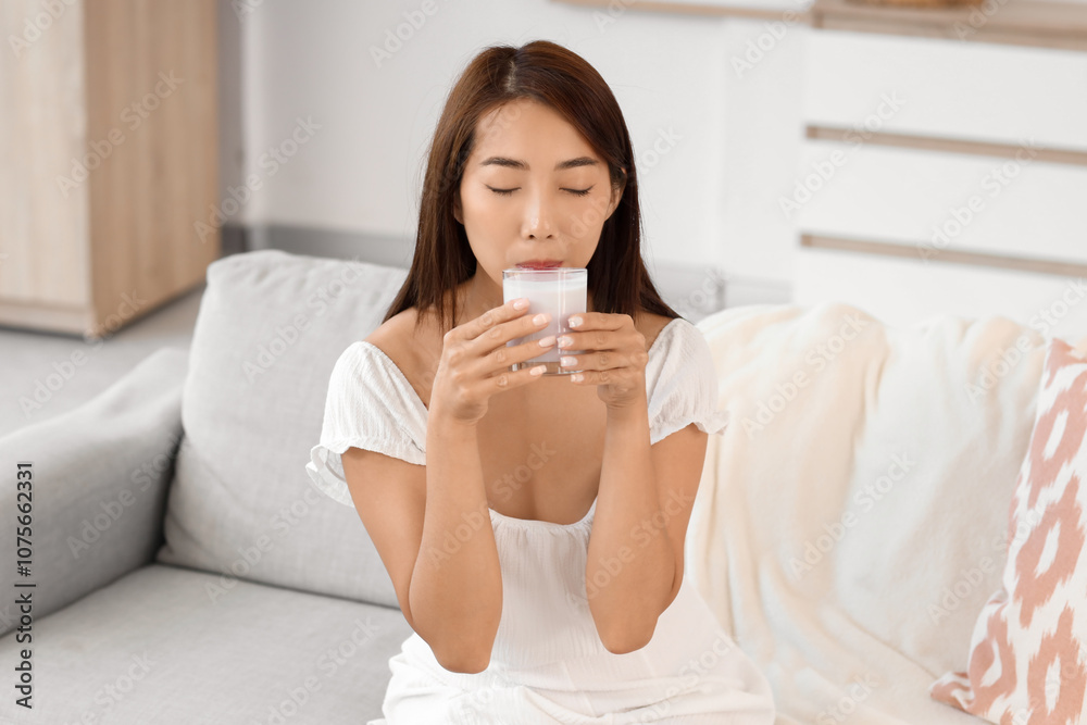 Pretty young Asian woman with glass of tasty yogurt at home Pretty young Asian woman with glass of tasty yogurt at home