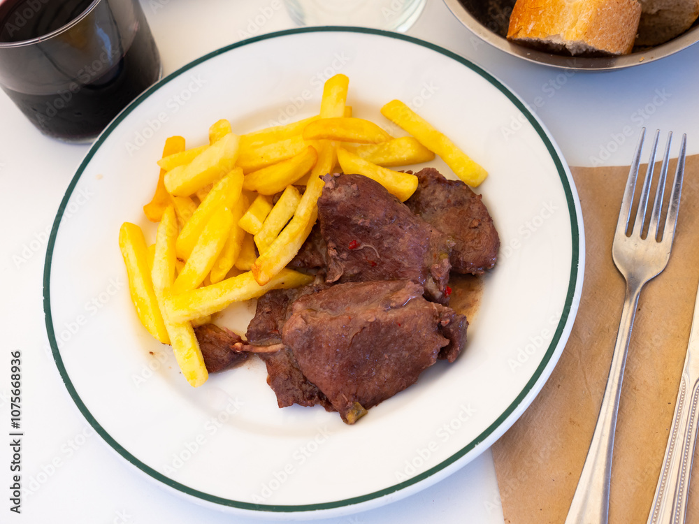 Spanish Secreto de cerdo - fried pork in red, served with french fries Spanish Secreto de cerdo - fried pork in red, served with french fries