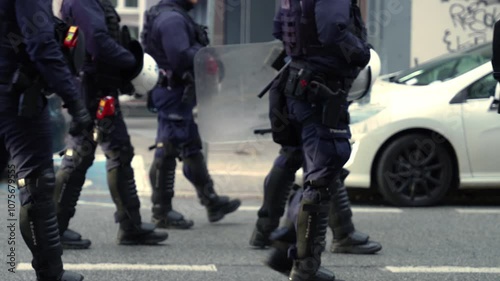 A large march in a European city, escorted by police officers.