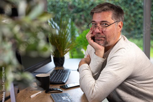 portrait d'un employé de bureau ou d'un homme d'affaires qui est assis à son bureau devant son ordinateur il est souriant et sympathique. Il est heureux de travailler chez lui à distance photo