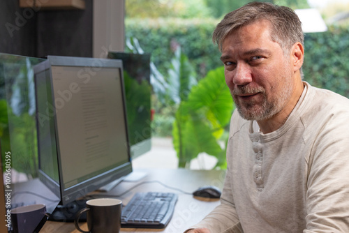 portrait d'un employé de bureau ou d'un homme d'affaires qui est assis à son bureau devant son ordinateur il est souriant et sympathique. Il est heureux de travailler chez lui à distance