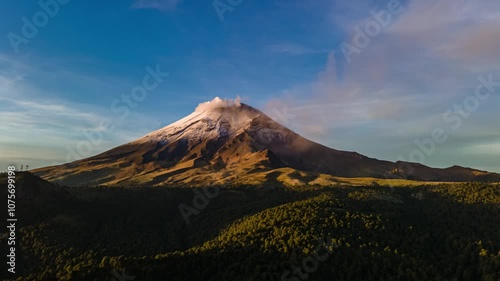Lateral aerial hyperlapse of the active Popocatepetl volcano captured at sunrise during the golden hour. A stunning view showcasing the majesty of the volcanic landscape and the soft morning light.