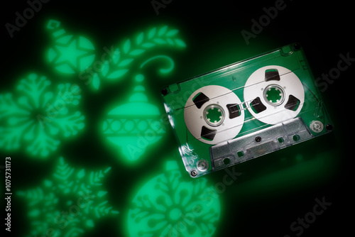 Christmas music theme background. Green light projections of christmas tree toys on a dark background and an audio cassette photo