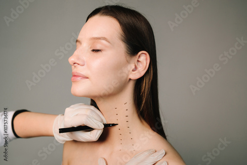 Cosmetologist is drawing dotes before botulinum toxin injection in platysma of a woman. Mark up before Nefertiti lifting. Improving neck by a professional. Female aesthetic cosmetology. photo