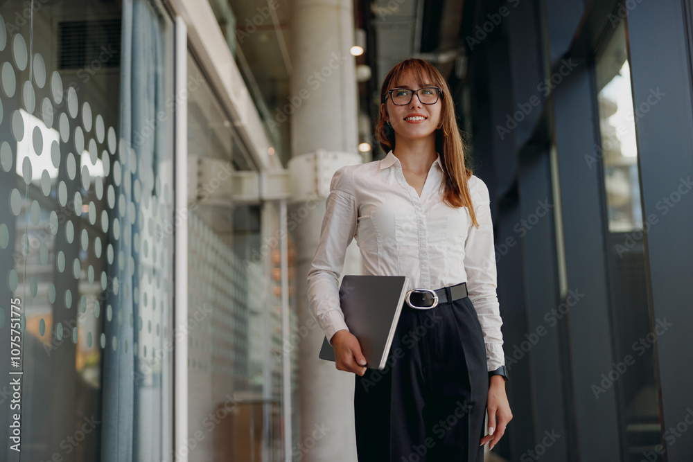 A professional woman is smiling confidently while situated in a sleek and modern office environment that inspires A professional woman is smiling confidently while situated in a sleek and modern office environment that inspires