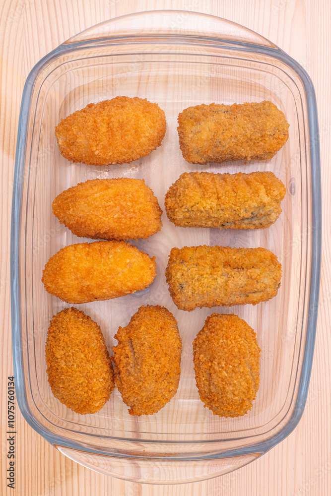 Chicken mushroom and cod croquettes arranged in a glass container on a wooden table Chicken mushroom and cod croquettes arranged in a glass container on a wooden table