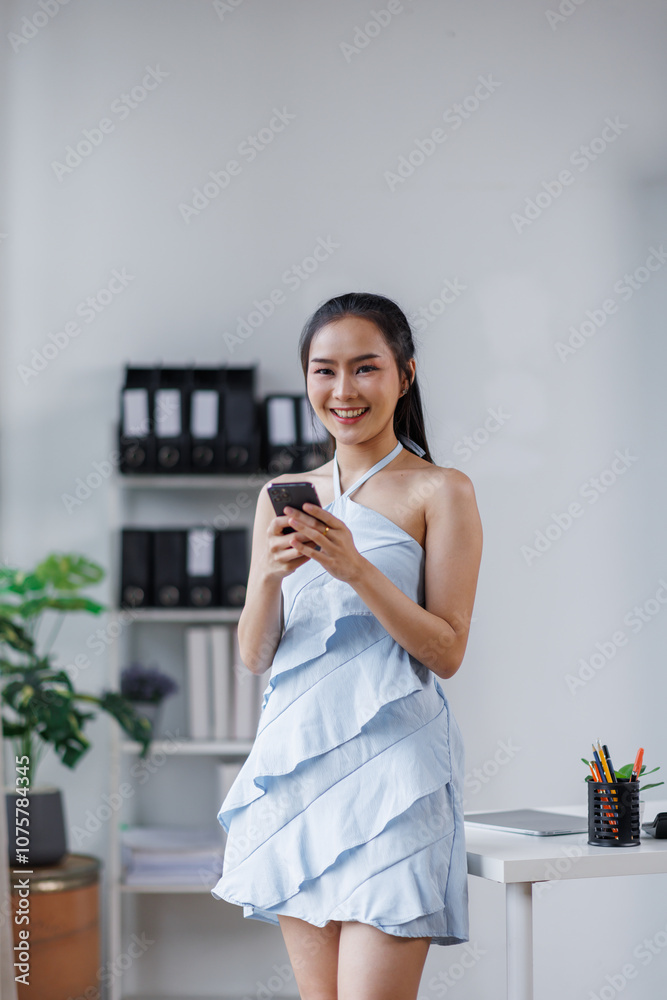 Cheerful beautiful Asian woman holding smartphone in the office workplace,
Cheerful beautiful Asian woman holding smartphone in the office workplace,