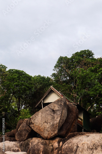 A small beach hut is surrounded by rocks, boulders and lush green trees on Koh Tao Island in Thailand