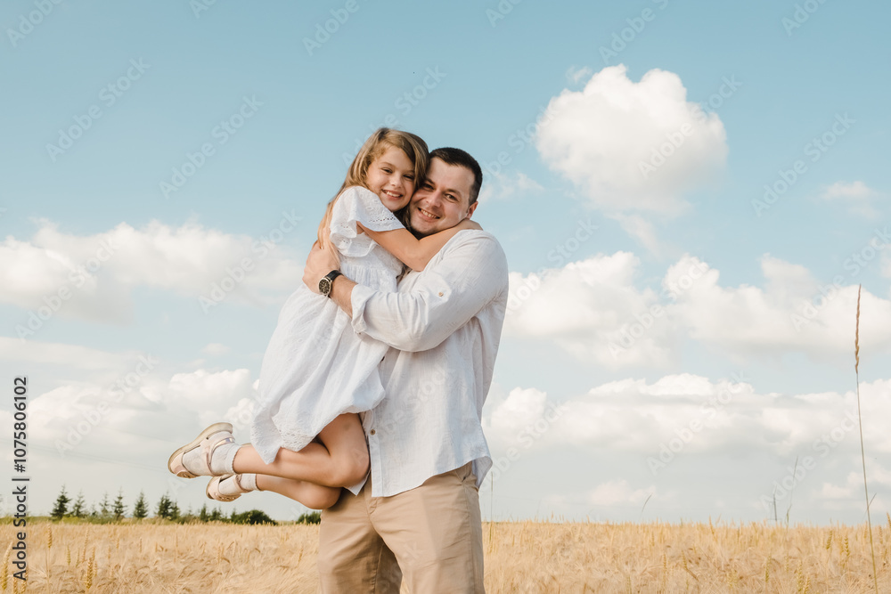 farmer carries little daughter in his arms through a field of wheat. happy child and father are playing in field of ripening wheat.Beautiful daughter kisses and hugs her dad. farmer carries little daughter in his arms through a field of wheat. happy child and father are playing in field of ripening wheat.Beautiful daughter kisses and hugs her dad.