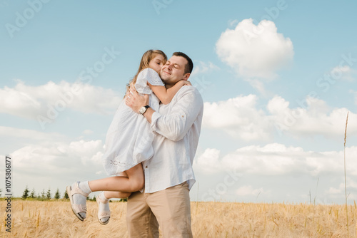 Dad with his daughter in his arms against the background of nature. They play together, laugh, hug and kiss