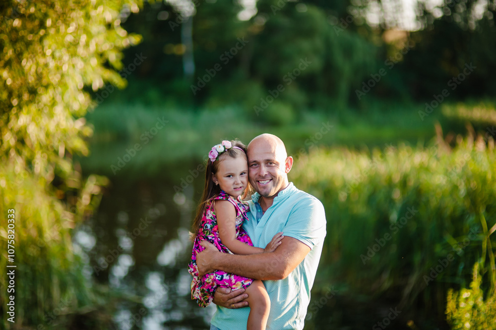Fototapeta premium Portrait of a beautiful child in nature. Little girl in a bright dress. Dad and baby playing in nature.