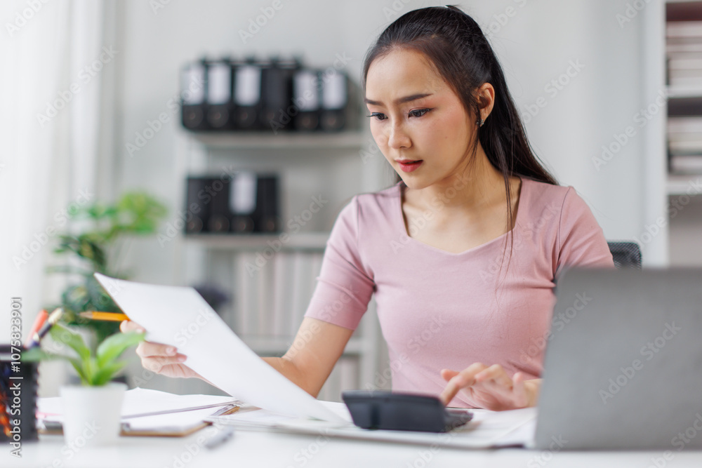 Portrait of tired young business Asian woman work with documents tax laptop computer in office. Sad, unhappy, Worried, Depression, or employee life stress concept
