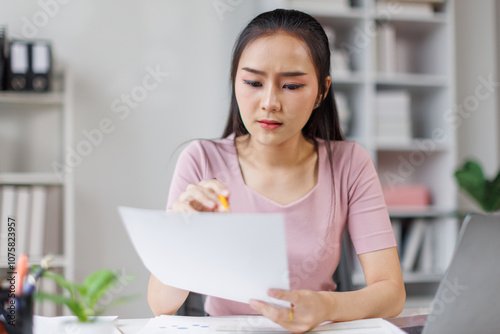 Portrait of tired young business Asian woman work with documents tax laptop computer in office. Sad, unhappy, Worried, Depression, or employee life stress concept 