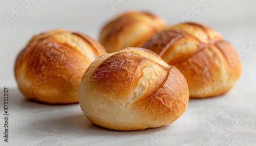 Four freshly baked bread rolls with a crispy crust on a white background.