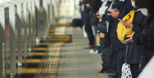 朝の通勤時間の駅のホームで電車待ちの人々の姿