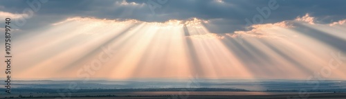 A breathtaking view of sunlight breaking through clouds, creating radiant beams shining over a tranquil landscape.