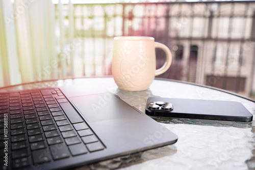 Remotely working from home on your computer and cellphone and enjoying hot and fresh coffee white watching sunset on your balcony