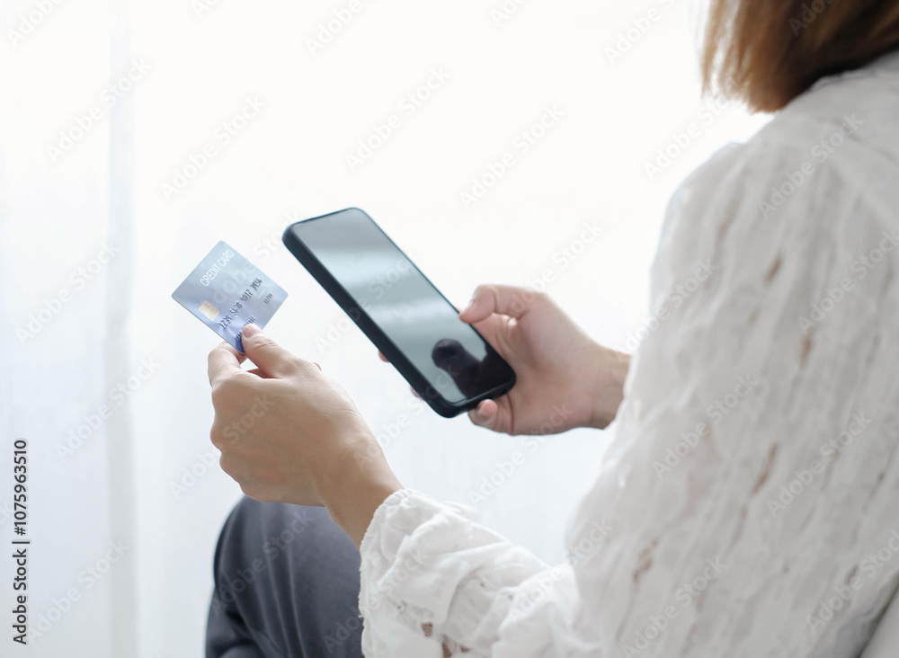 Asian girl shopping online holding credit and using smartphone enter their card number in the mobile phone app to purchase and payment in internet store Asian girl shopping online holding credit and using smartphone enter their card number in the mobile phone app to purchase and payment in internet store
