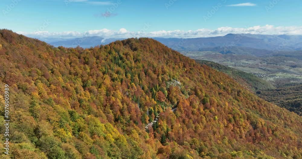 Aerial view of vibrant autumn foliage covering a mountainous landscape, showcasing a stunning array of red, orange, yellow, and green trees under a bright blue sky Aerial view of vibrant autumn foliage covering a mountainous landscape, showcasing a stunning array of red, orange, yellow, and green trees under a bright blue sky